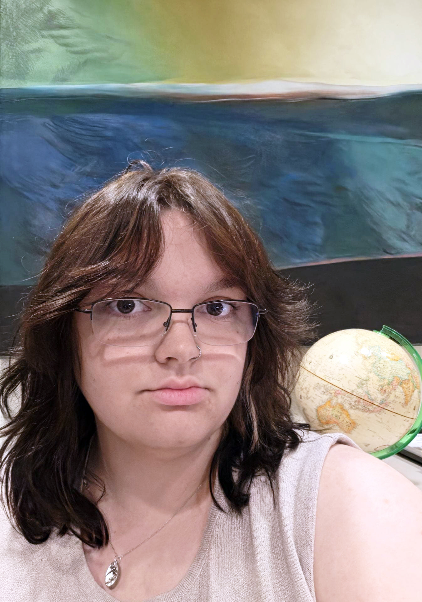 Young person with short brown hair and glasses